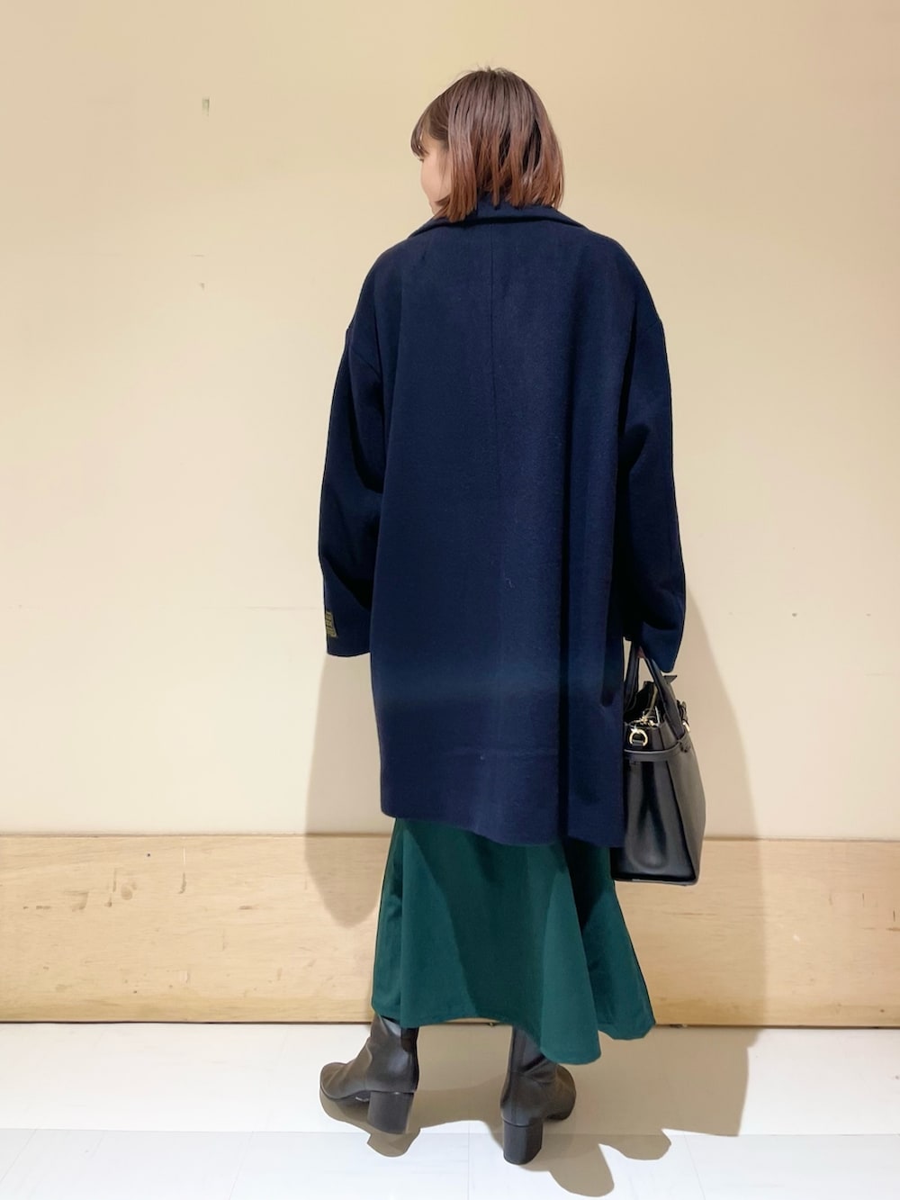 グリーン系のワンピース、ブルー系のピーコート、ブラック系のブーツを着用したレディースの冬コーディネートの5枚目の写真