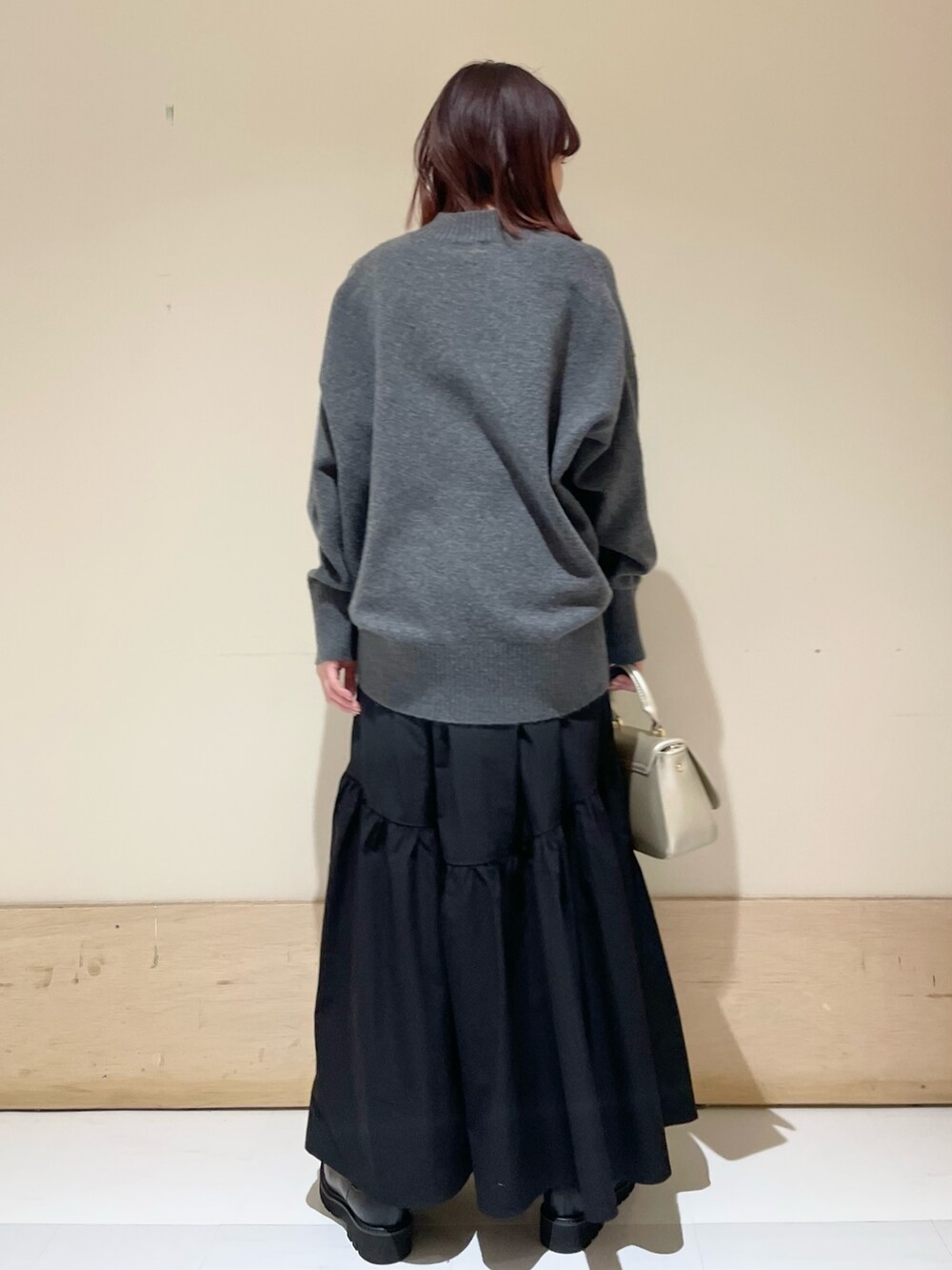 ブラック系のスカート、ゴールド系のショルダーバッグ、ブラック系のブーツを着用したレディースの冬コーディネートの5枚目の写真