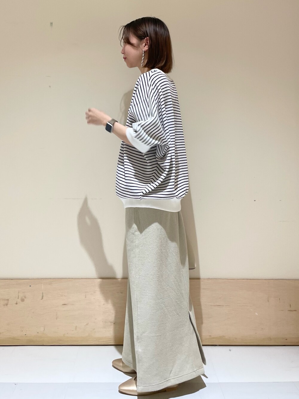 ベージュ系のスカート、ホワイト系のTシャツ/カットソー、ホワイト系のトートバッグを着用したレディースの秋コーディネートの4枚目の写真