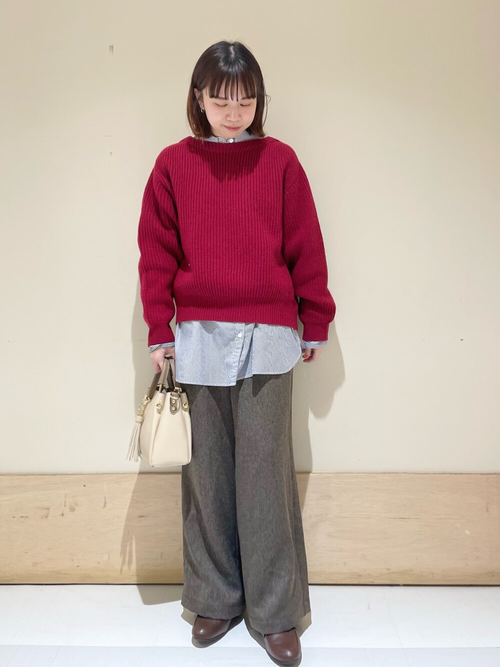 レッド系のニット/セーター、ブラウン系のその他パンツ、ブルー系のシャツ/ブラウスを着用したレディースの冬コーディネートの3枚目の写真