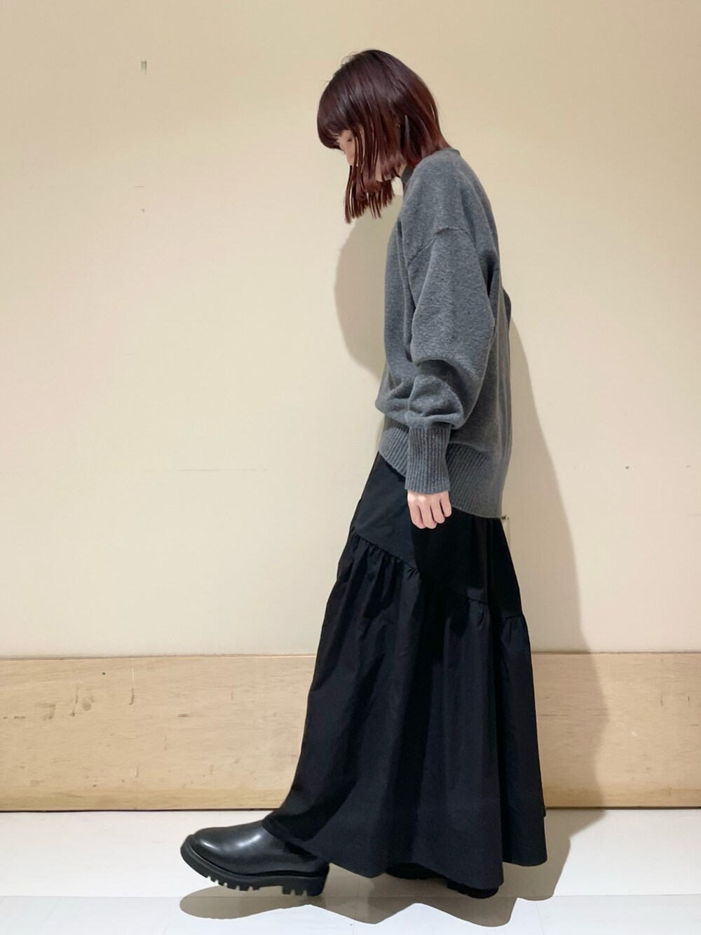 ブラック系のスカート、ゴールド系のショルダーバッグ、ブラック系のブーツを着用したレディースの冬コーディネートの4枚目の写真