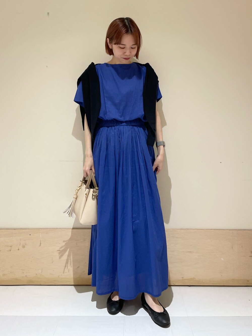 ブルー系のワンピース、ブラック系のカーディガン/ボレロ、ホワイト系のトートバッグを着用したレディースの春コーディネートの2枚目の写真