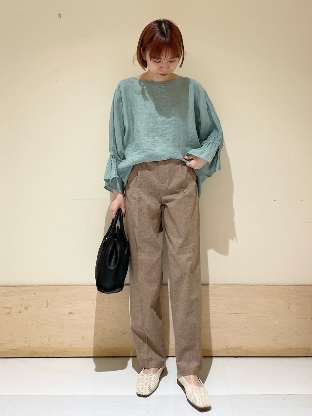 グリーン系のシャツ/ブラウス、ブラック系のトートバッグ、ホワイト系のバレエシューズを着用したレディースの春コーディネートの2枚目の写真