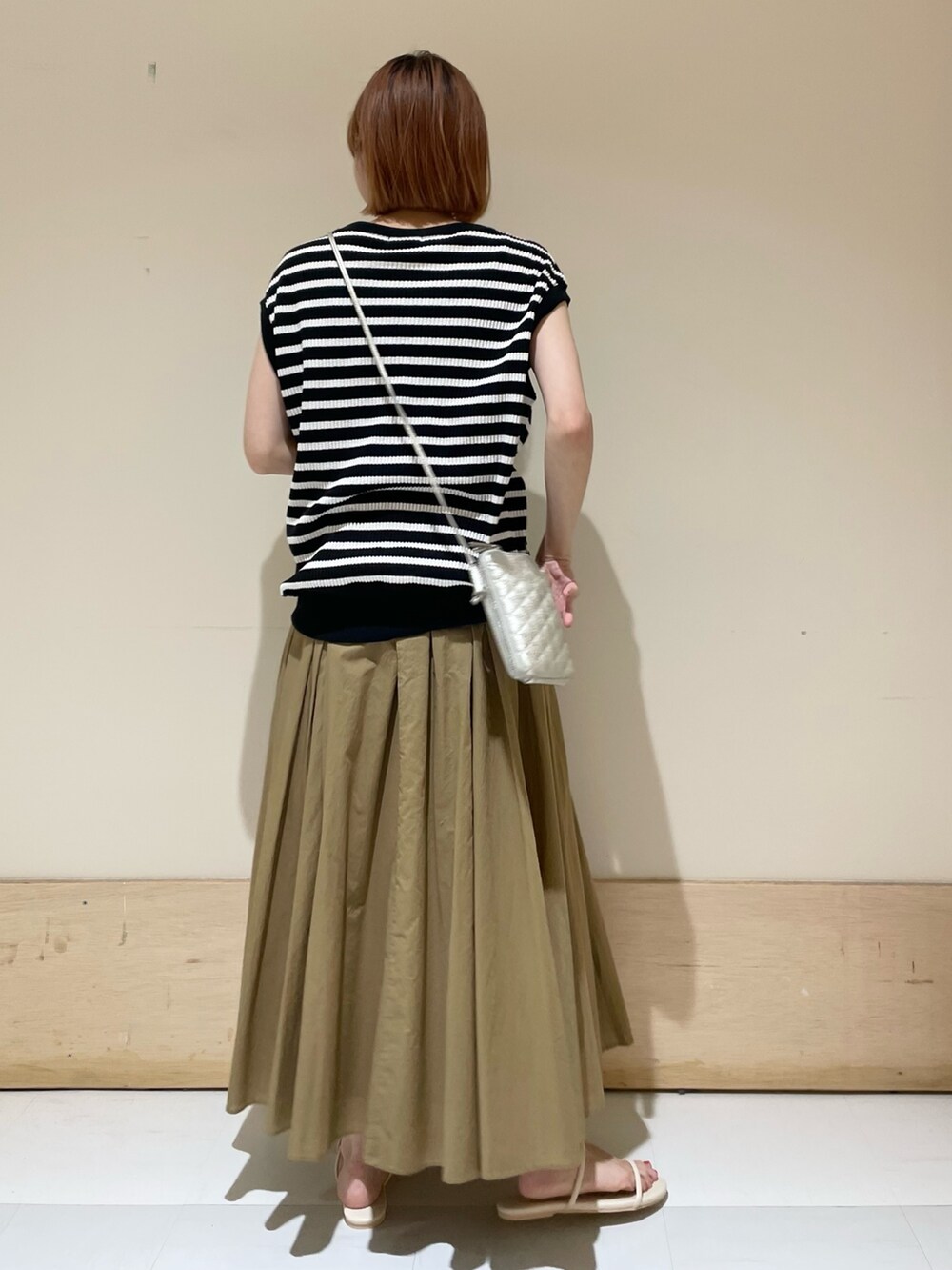 ベージュ系のスカート、ホワイト系のサンダル、ブラック系のTシャツ/カットソーを着用したレディースの夏コーディネートの5枚目の写真