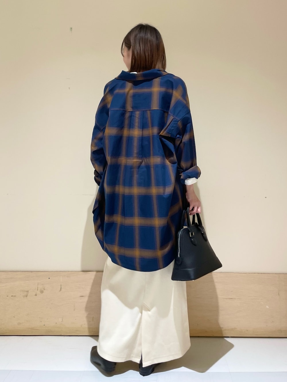 ベージュ系のスカート、ブラック系のパンプス、ブラック系のショルダーバッグを着用したレディースの秋コーディネートの6枚目の写真