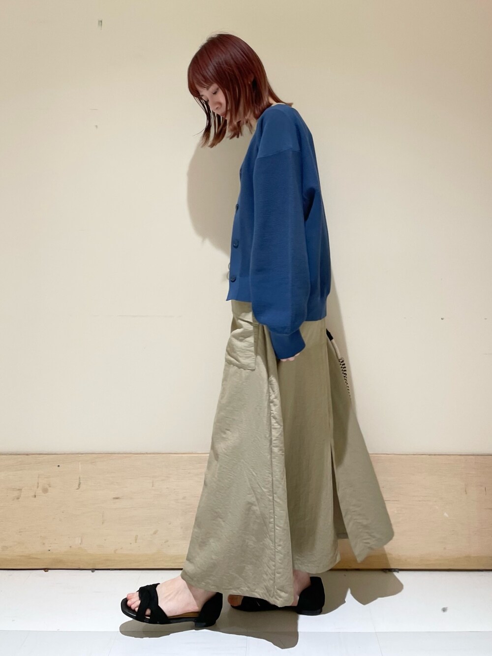 ベージュ系のワンピース、ブルー系のニット/セーター、ブラック系のショルダーバッグを着用したレディースの春コーディネートの4枚目の写真