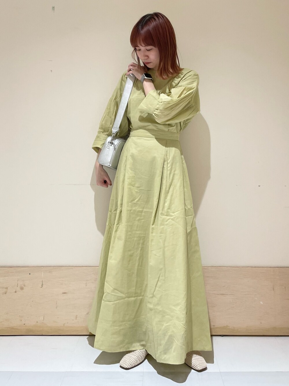 グリーン系のワンピース、シルバー系のショルダーバッグ、ホワイト系のパンプスを着用したレディースの春コーディネートの2枚目の写真