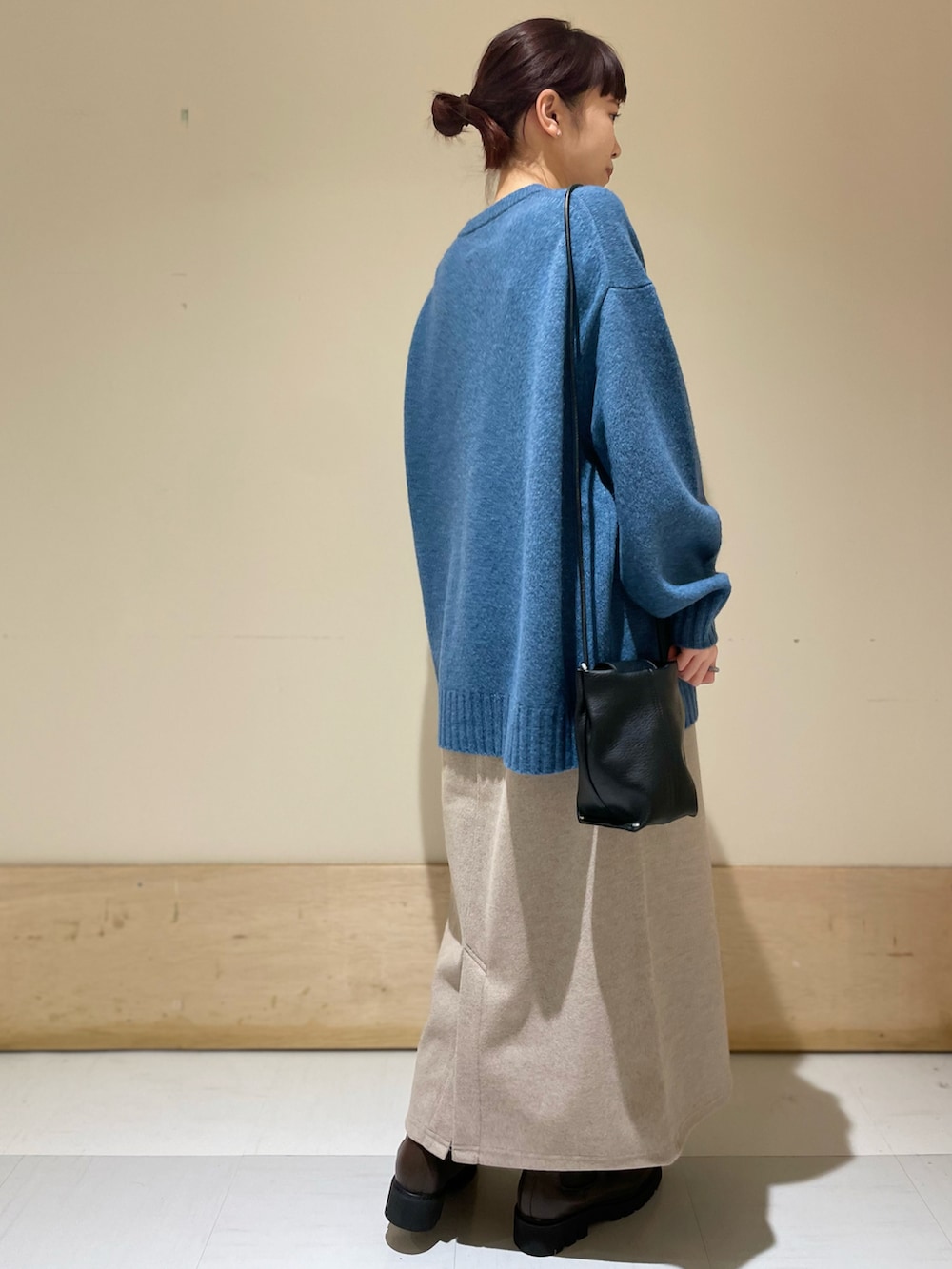 ブルー系のニット/セーター、ベージュ系のスカート、ブラック系のショルダーバッグを着用したレディースの冬コーディネートの3枚目の写真