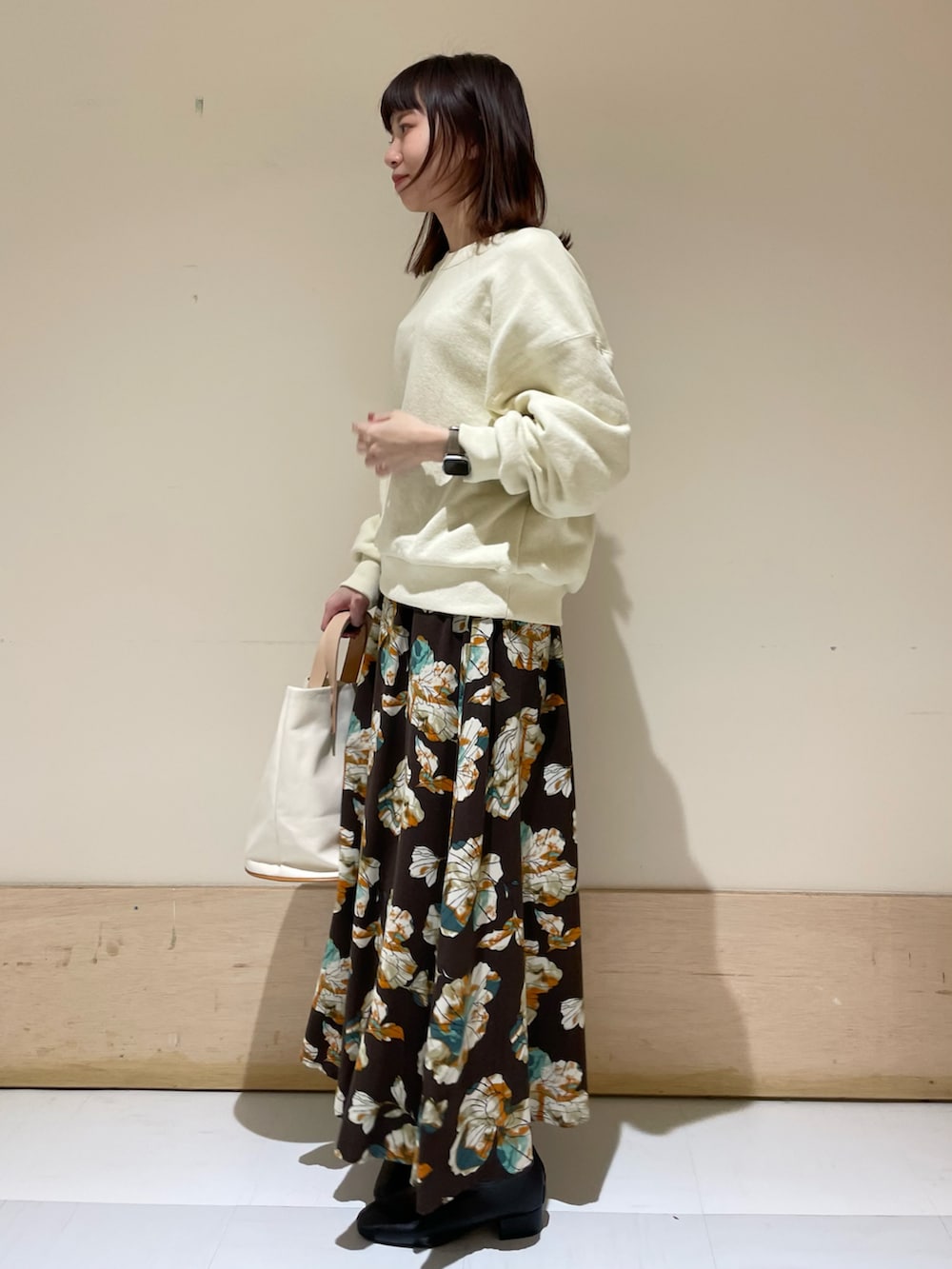 ホワイト系のスウェット、ブラウン系のスカート、ブラック系のブーツを着用したレディースの冬コーディネートの3枚目の写真