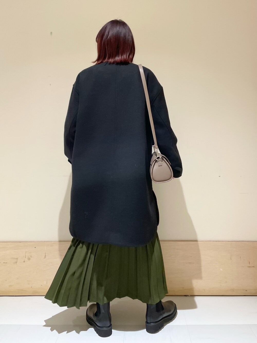 ブラック系のその他アウター、ブラック系のブーツ、グリーン系のスカートを着用したレディースの冬コーディネートの4枚目の写真