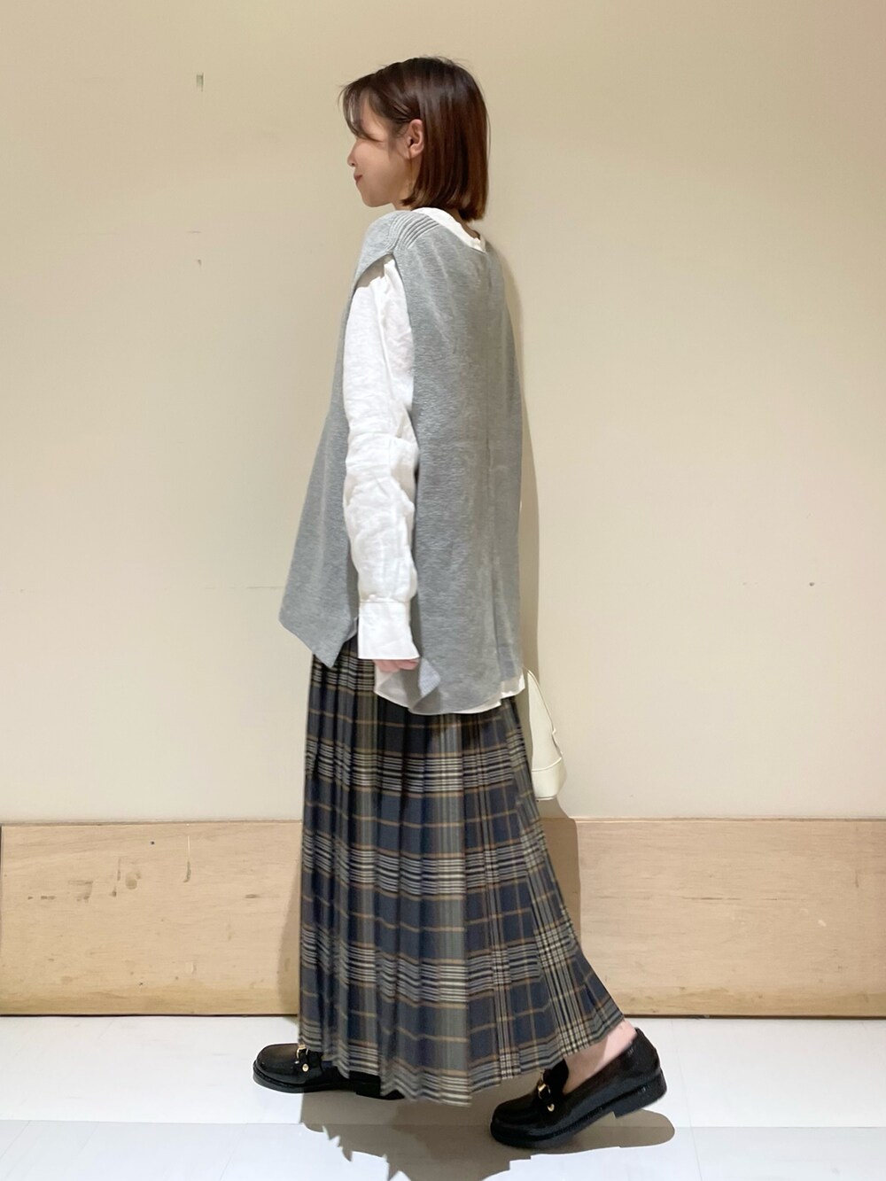 グレー系のベスト、ホワイト系のTシャツ/カットソー、ブラック系のレインシューズを着用したレディースの秋コーディネートの5枚目の写真