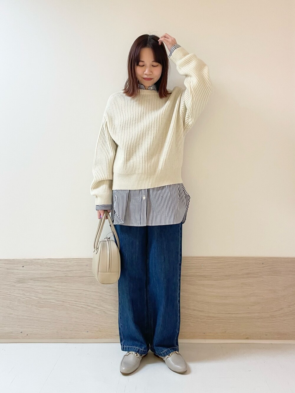 ホワイト系のニット/セーター、ブルー系のデニムパンツ、ベージュ系のボストンバッグを着用したレディースの冬コーディネートの3枚目の写真