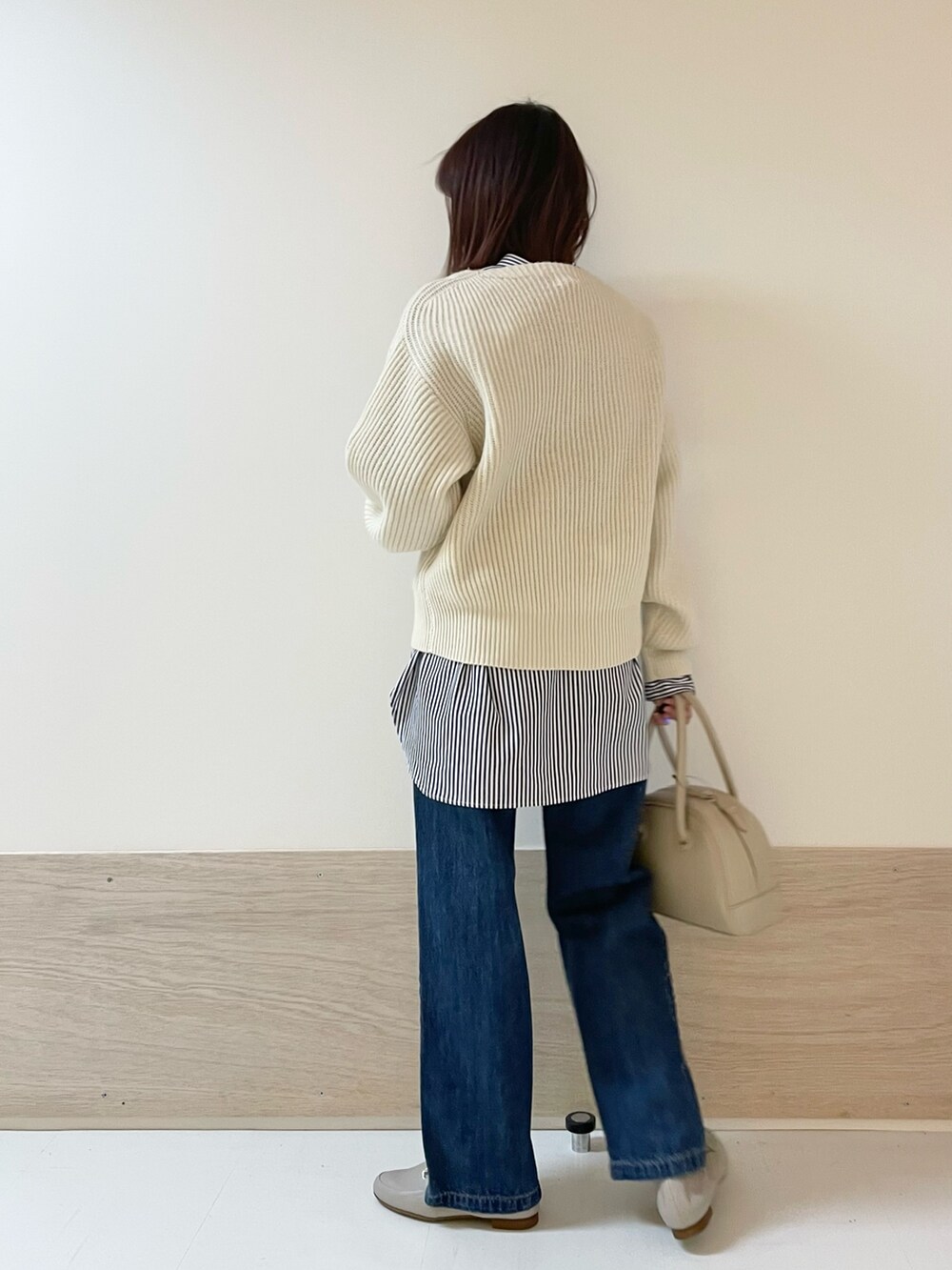 ホワイト系のニット/セーター、ブルー系のデニムパンツ、ベージュ系のボストンバッグを着用したレディースの冬コーディネートの5枚目の写真