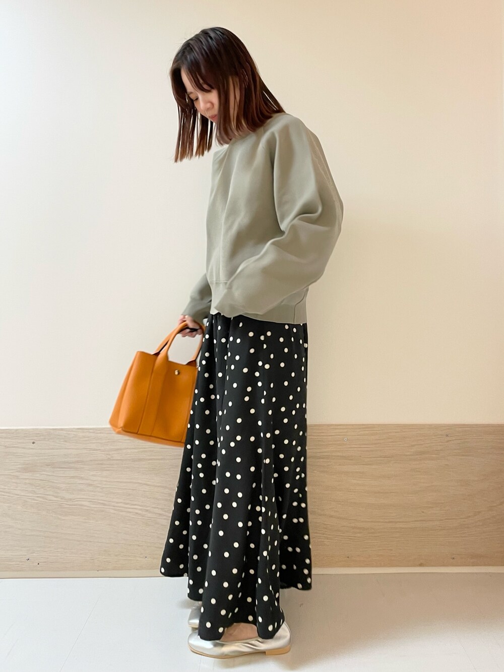 ブラック系のスカート、シルバー系のバレエシューズ、グリーン系のニット/セーターを着用したレディースの春コーディネートの2枚目の写真