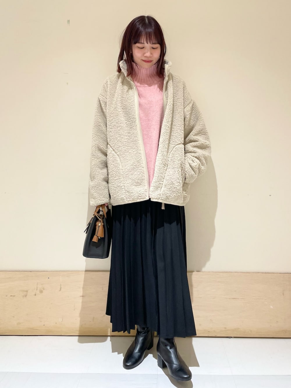 ピンク系のニット/セーター、ホワイト系のブルゾン、ブラック系のスカートを着用したレディースの冬コーディネートの2枚目の写真