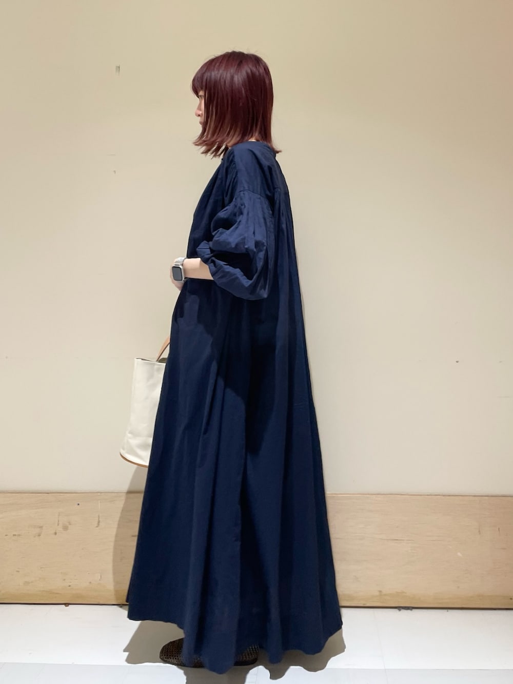 ホワイト系のトートバッグ、ブルー系のワンピース、ブラウン系のパンプスを着用したレディースの春コーディネートの6枚目の写真