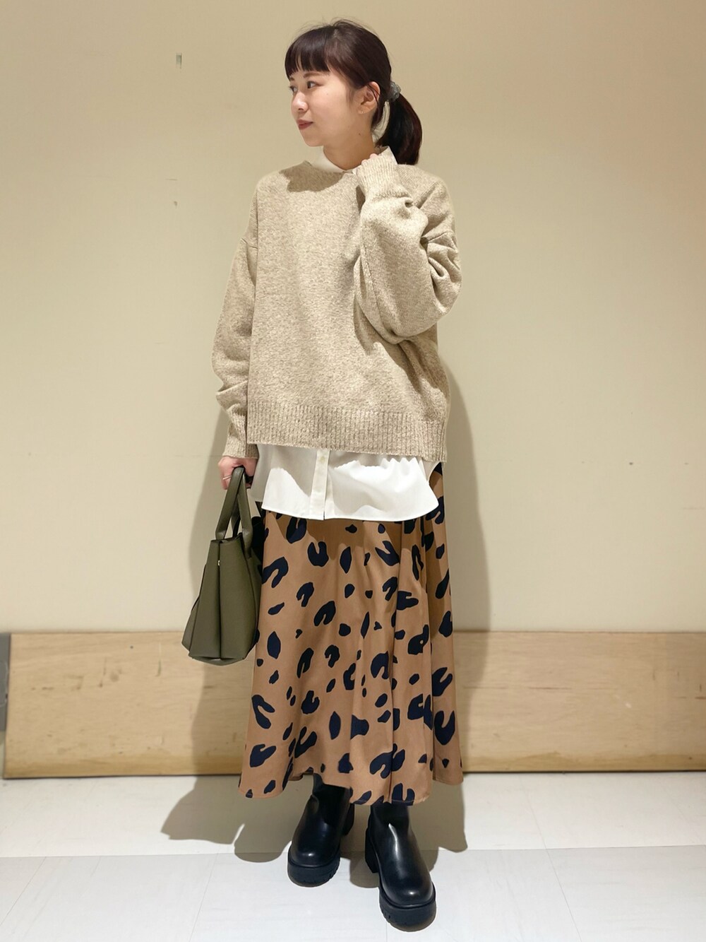 ベージュ系のニット/セーター、ホワイト系のシャツ/ブラウス、イエロー系のスカートを着用したレディースの冬コーディネートの2枚目の写真