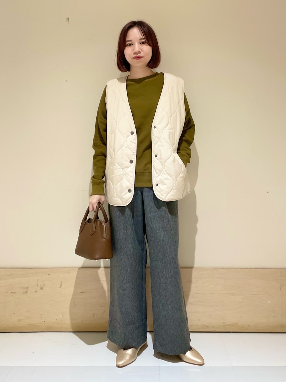 ゴールド系のパンプス、ブラウン系のショルダーバッグ、イエロー系のTシャツ/カットソーを着用したレディースの秋コーディネートの3枚目の写真