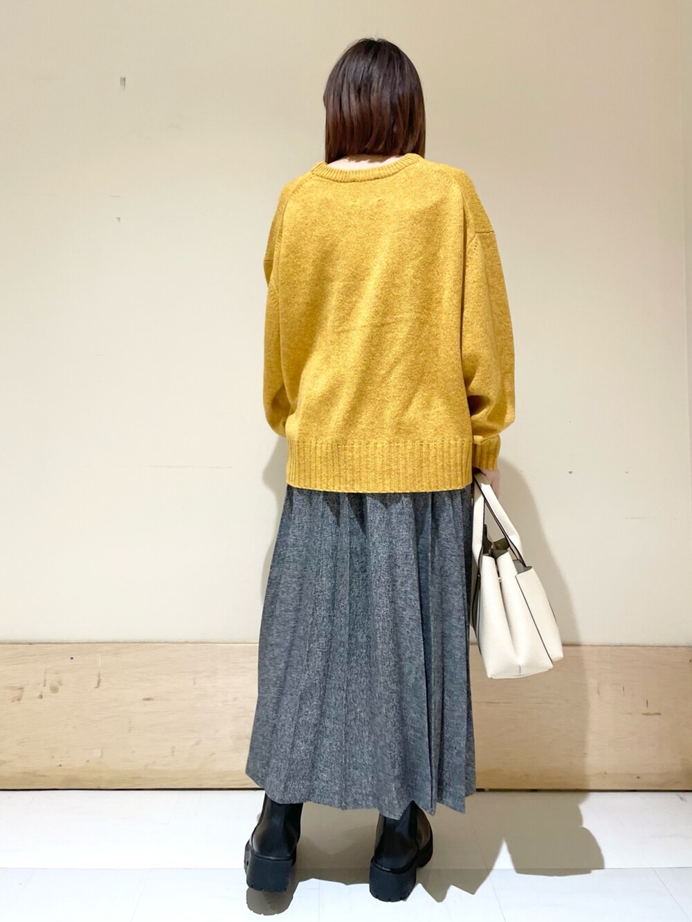 イエロー系のニット/セーター、ブルー系のスカート、ブラック系のブーツを着用したレディースの冬コーディネートの6枚目の写真