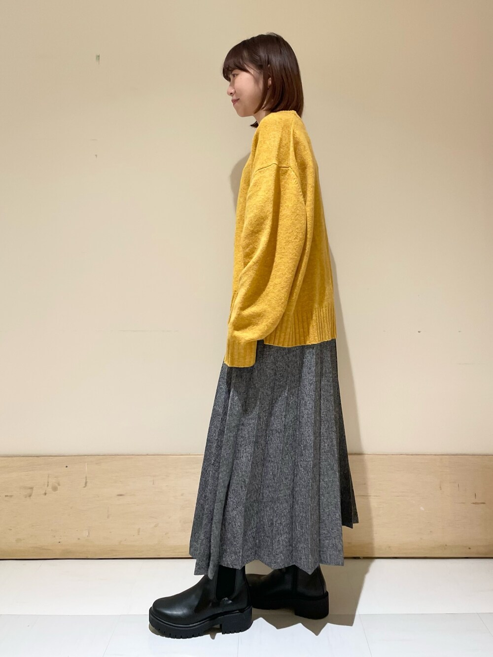 イエロー系のニット/セーター、ブルー系のスカート、ブラック系のブーツを着用したレディースの冬コーディネートの4枚目の写真