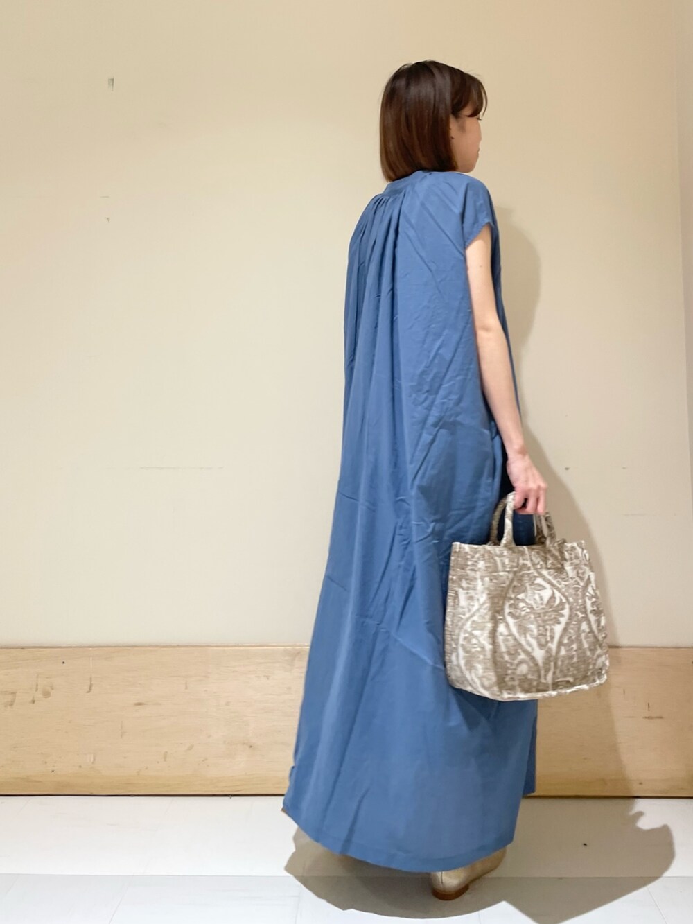 ブルー系のワンピース、ベージュ系のトートバッグ、ゴールド系のパンプスを着用したレディースの夏コーディネートの5枚目の写真
