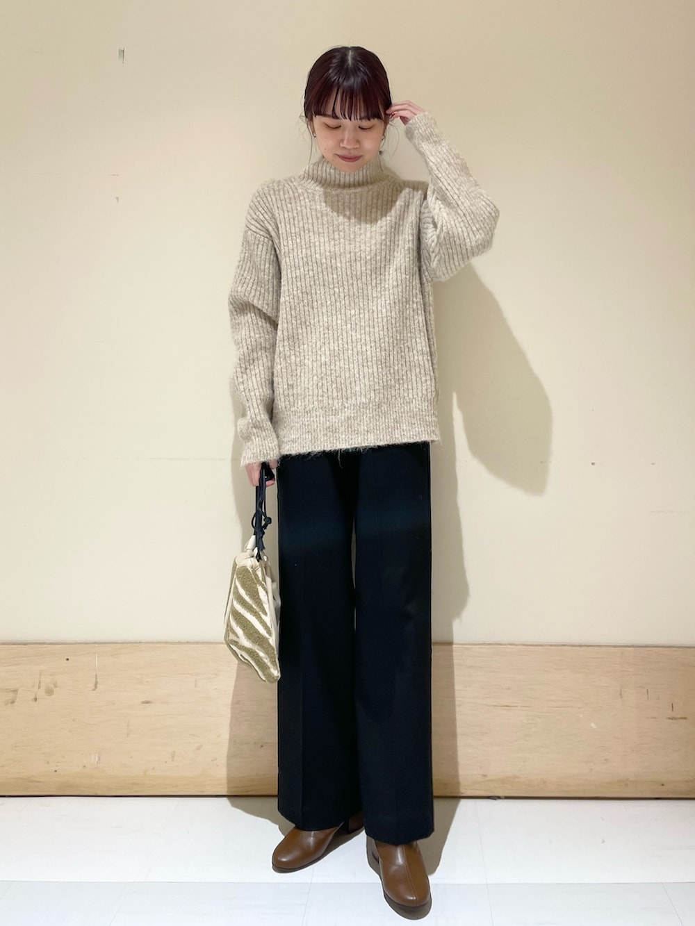 ブラック系のその他パンツ、ベージュ系のニット/セーター、ベージュ系のハンドバッグを着用したレディースの冬コーディネートの3枚目の写真