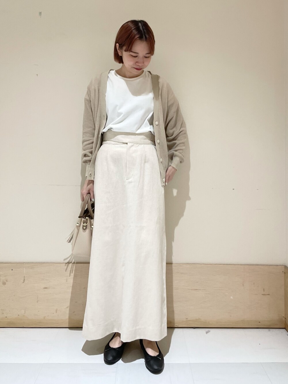 ベージュ系のスカート、ベージュ系のカーディガン/ボレロ、ホワイト系のTシャツ/カットソーを着用したレディースの春コーディネートの3枚目の写真
