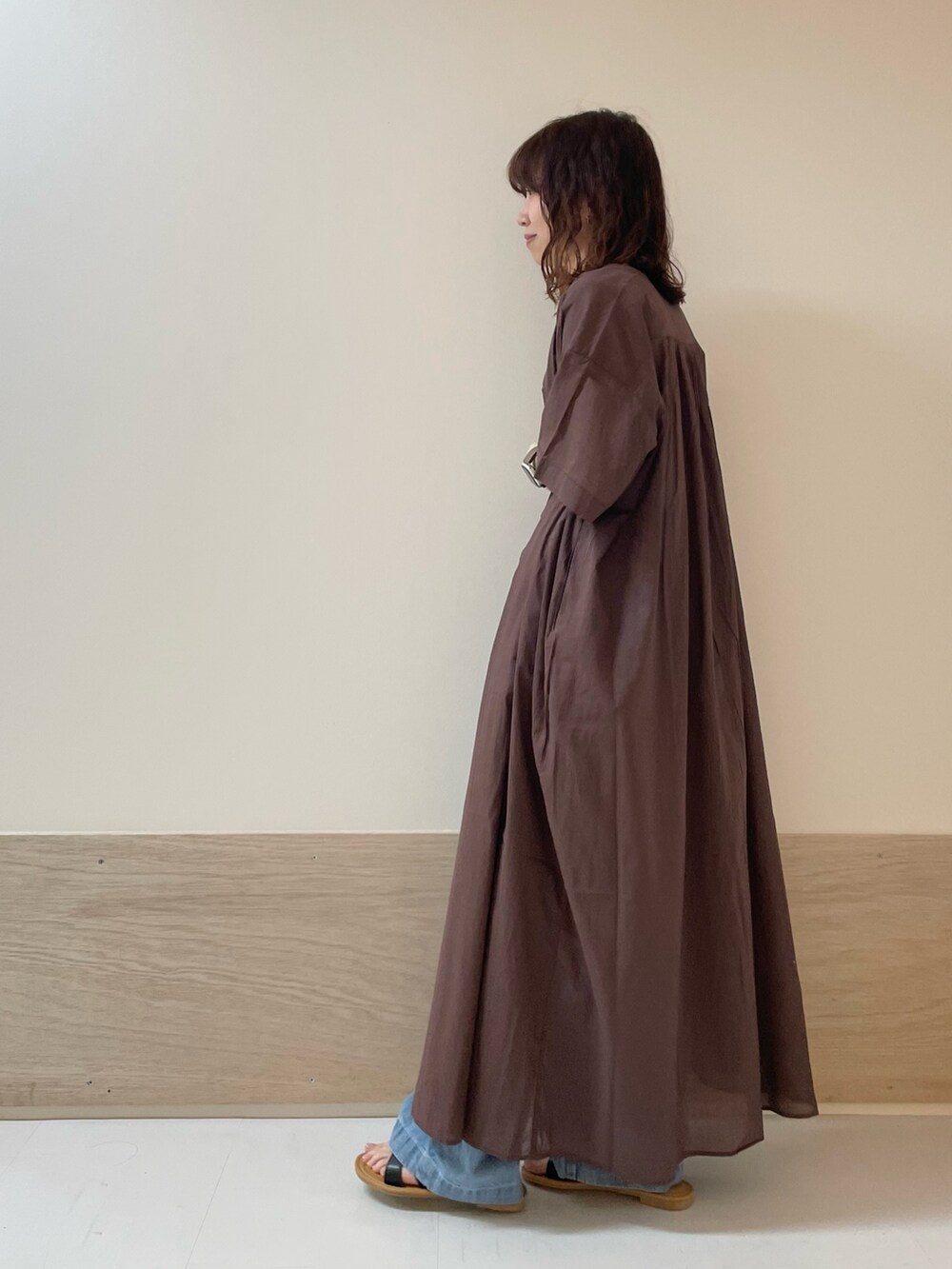 ブルー系のデニムパンツ、ブラック系のサンダル、ブラウン系のワンピースを着用したレディースの春コーディネートの7枚目の写真