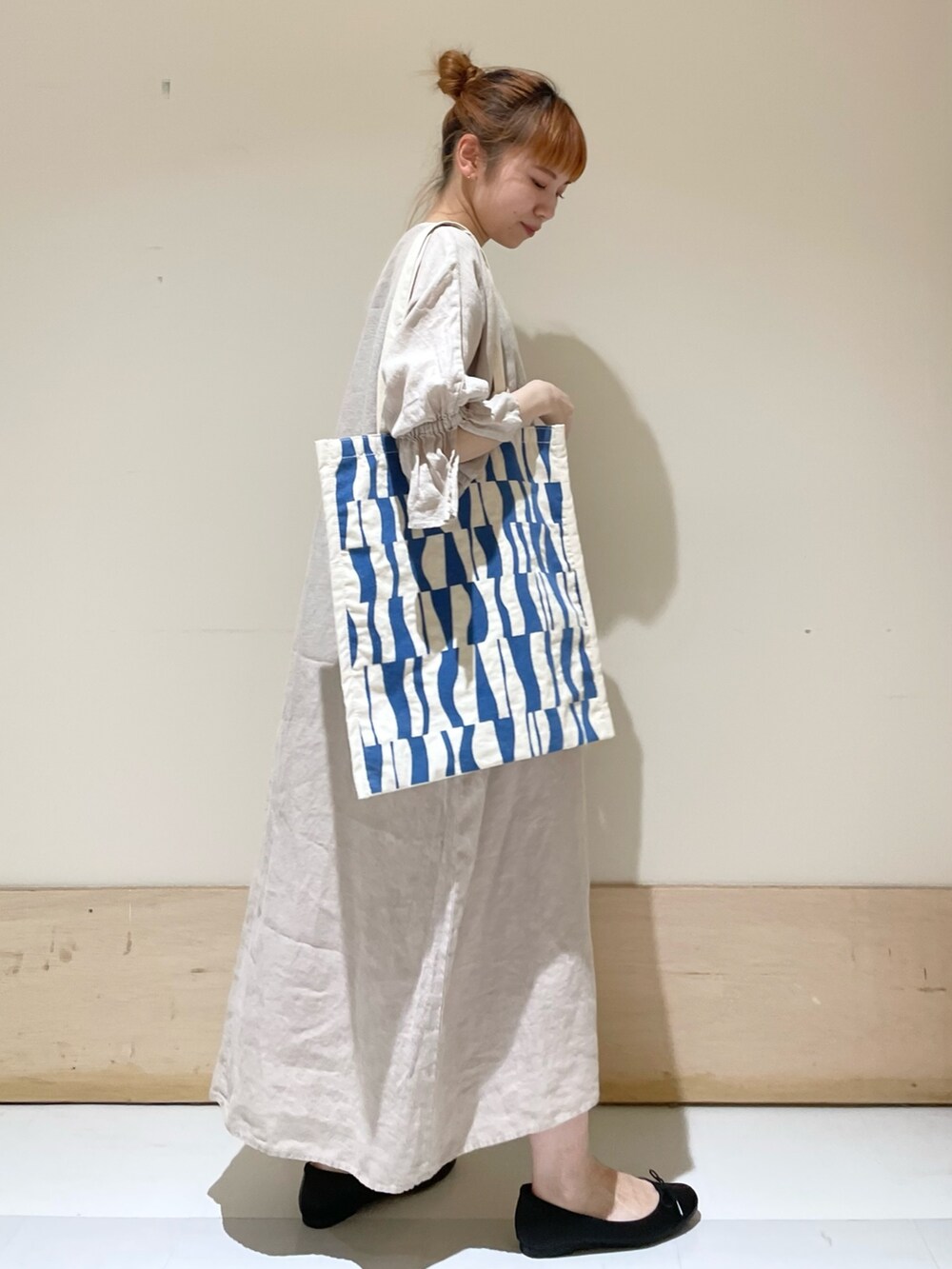 ベージュ系のワンピース、ブルー系のトートバッグ、ブラック系のバレエシューズを着用したレディースの春コーディネートの2枚目の写真