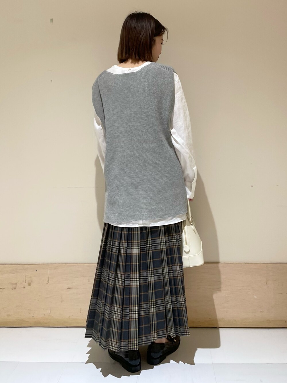 グレー系のベスト、ホワイト系のTシャツ/カットソー、ブラック系のレインシューズを着用したレディースの秋コーディネートの7枚目の写真