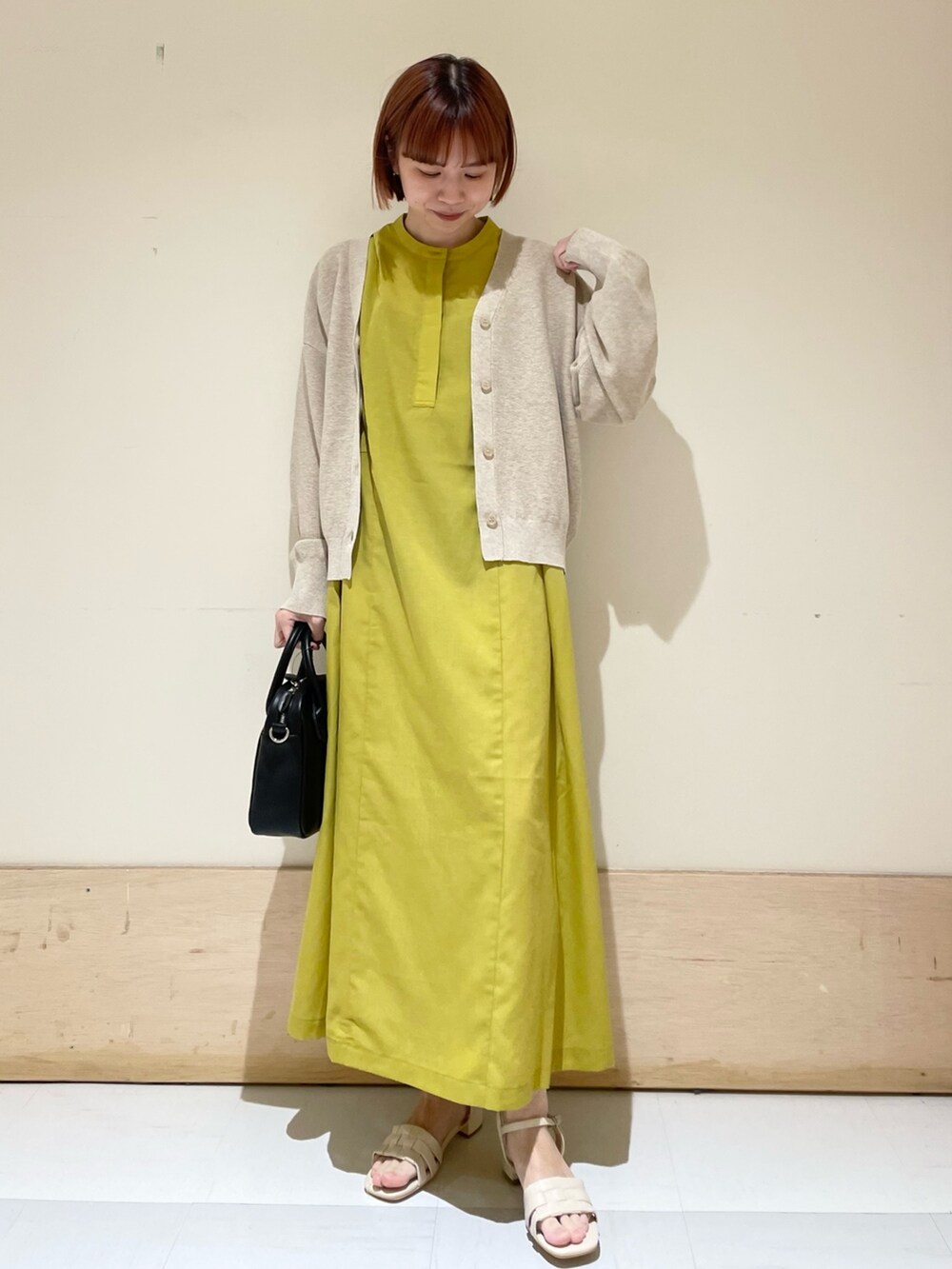 イエロー系のワンピース、ベージュ系のニット/セーター、ブラック系のショルダーバッグを着用したレディースの春コーディネートの5枚目の写真