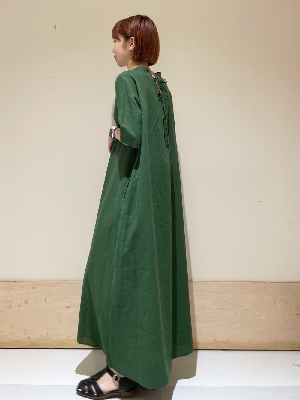 グリーン系のワンピース、ブラック系のサンダル、ブラック系のハンドバッグを着用したレディースの春コーディネートの5枚目の写真