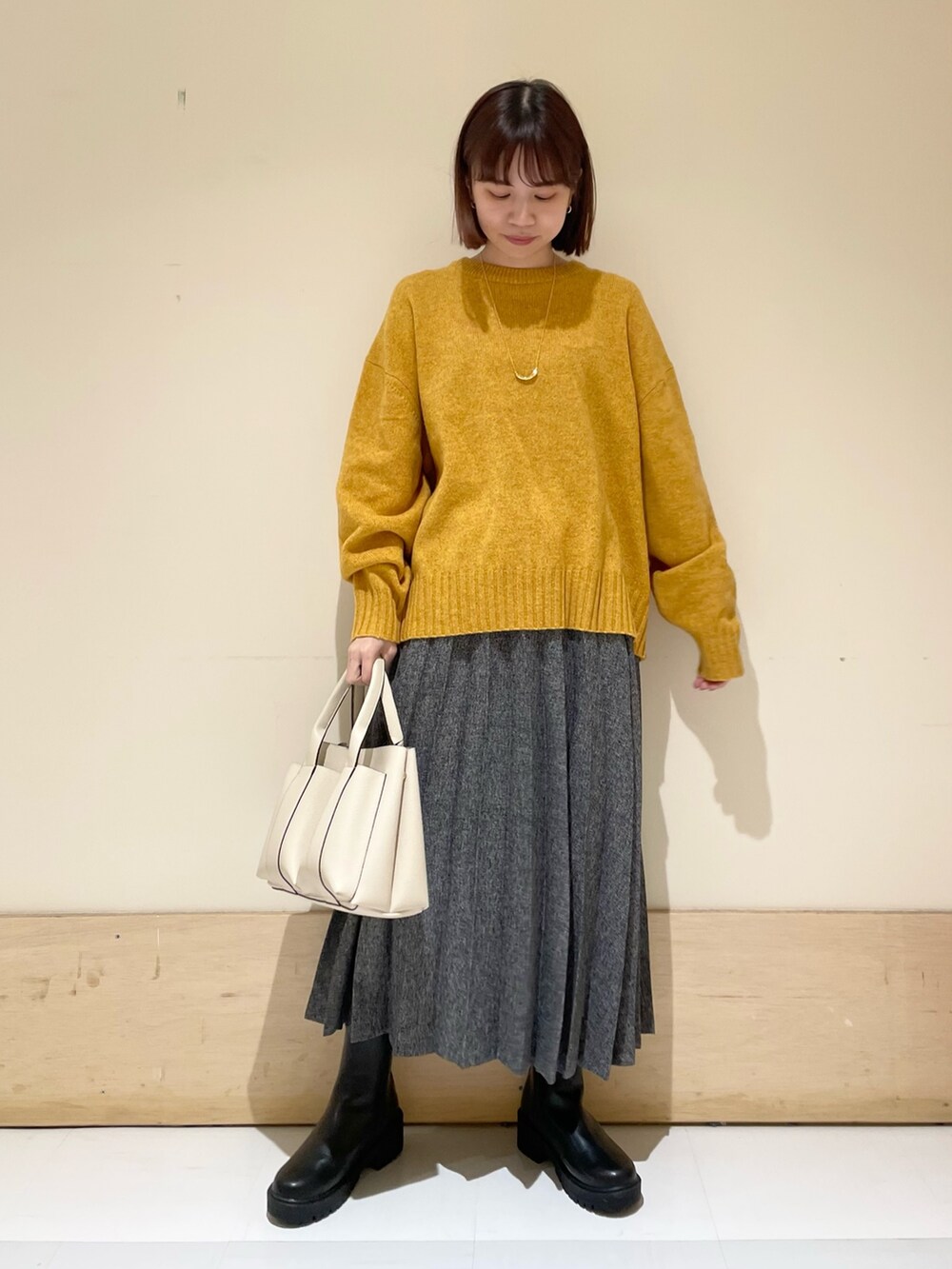 イエロー系のニット/セーター、ブルー系のスカート、ブラック系のブーツを着用したレディースの冬コーディネートの2枚目の写真