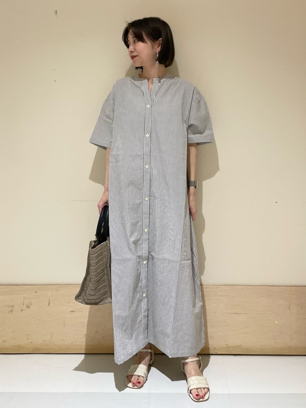 ベージュ系のトートバッグ、ホワイト系のサンダル、ブラック系のワンピースを着用したレディースの夏コーディネートの3枚目の写真