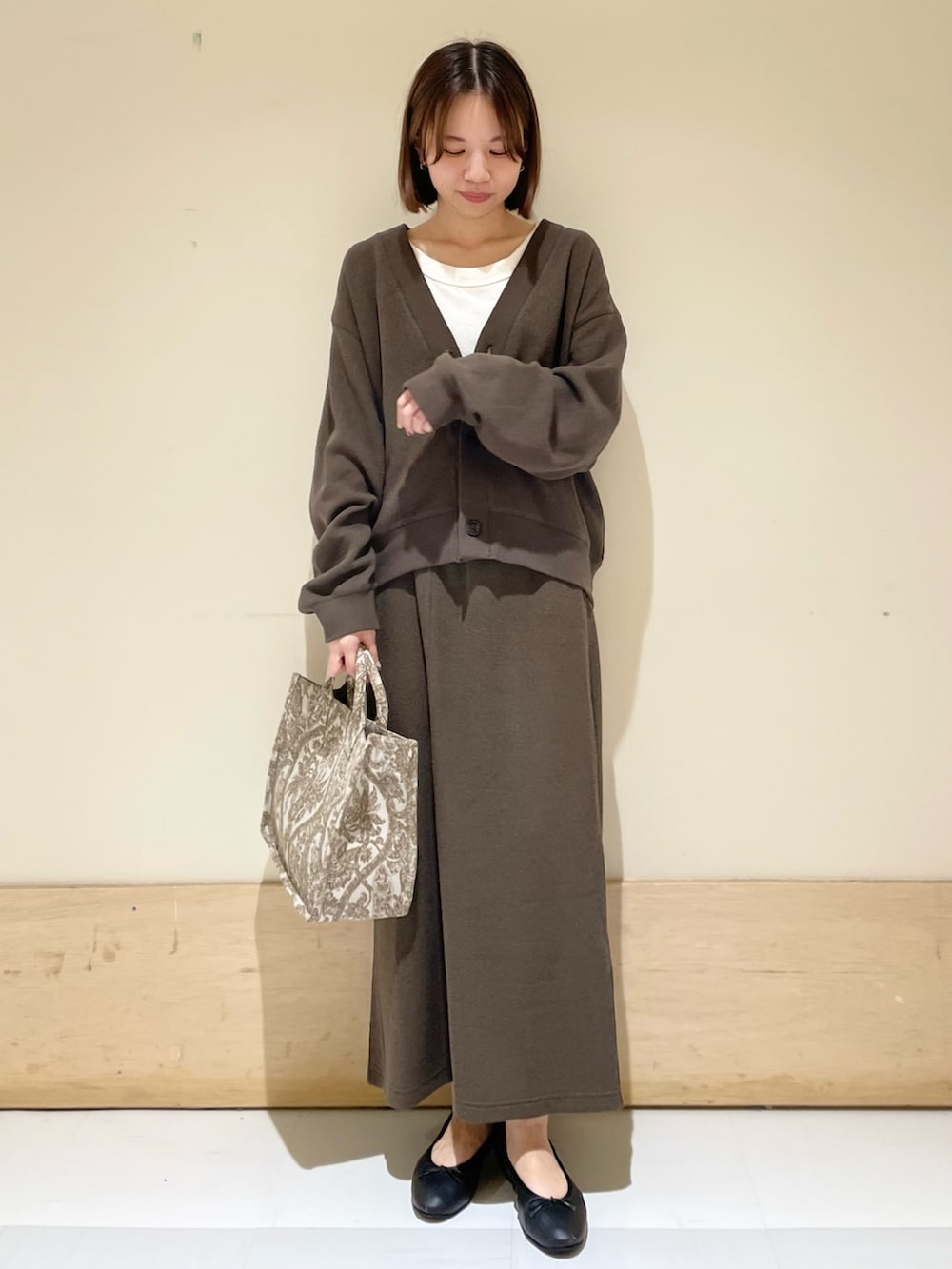 ベージュ系のトートバッグ、ホワイト系のタンクトップ、グレー系のカーディガン/ボレロを着用したレディースの秋コーディネートの2枚目の写真