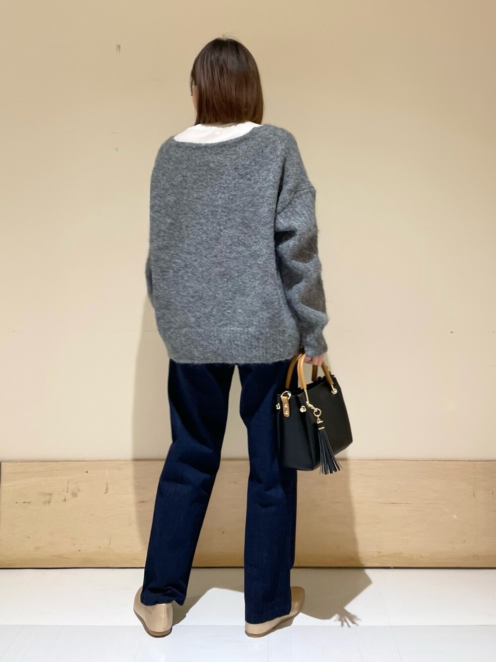 ゴールド系のパンプス、ブラック系のトートバッグ、ブルー系のデニムパンツを着用したレディースの秋コーディネートの4枚目の写真