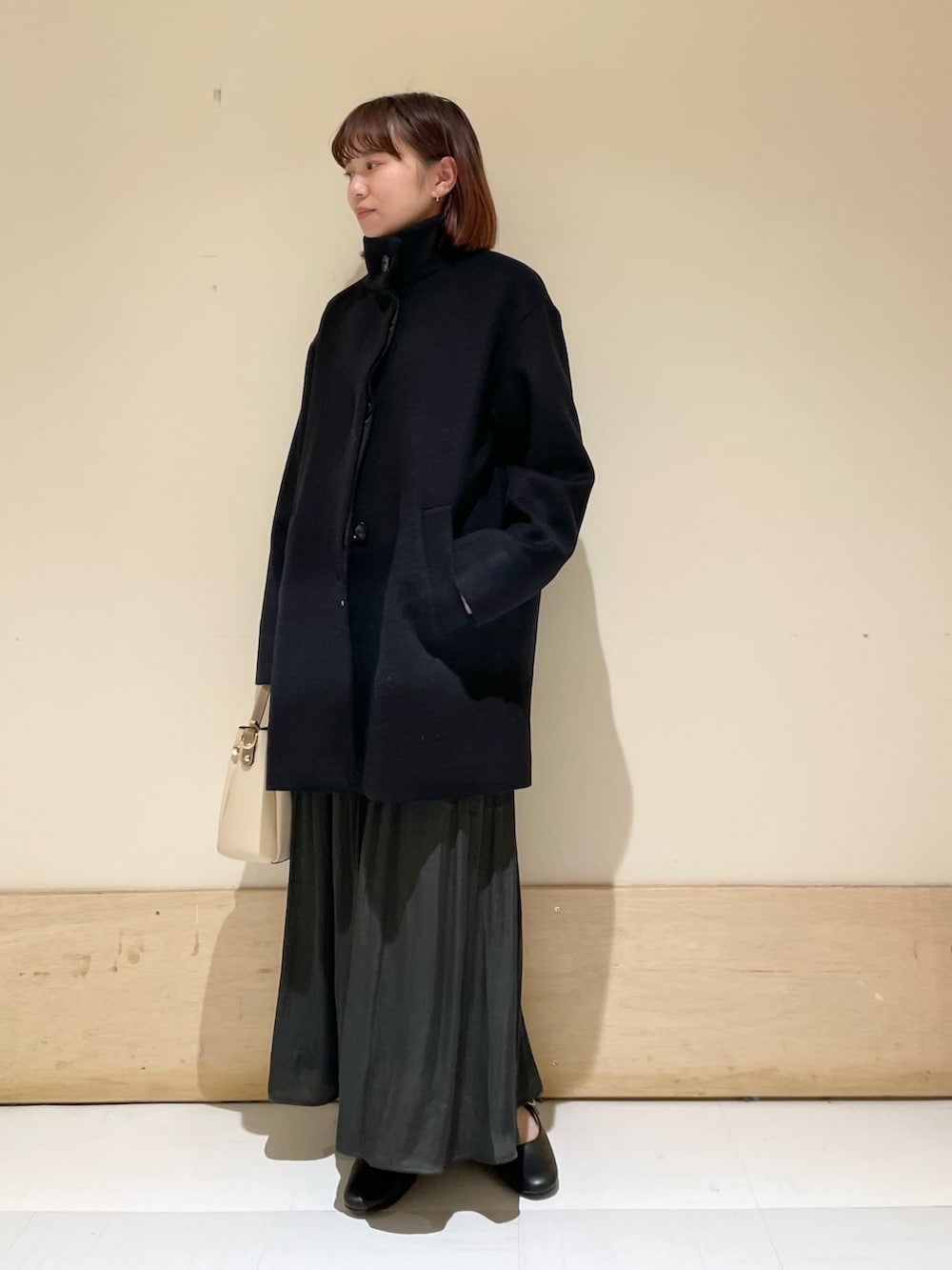 グリーン系のスカート、グレー系のニット/セーター、ブラック系のその他アウターを着用したレディースの冬コーディネートの4枚目の写真