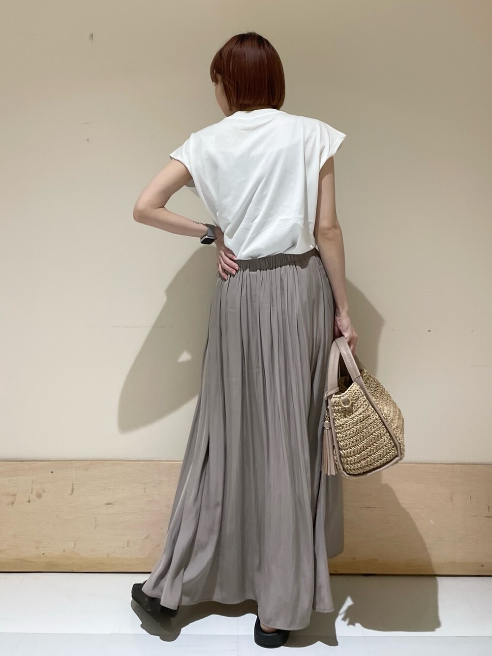 グレー系のスカート、ホワイト系のTシャツ/カットソー、ベージュ系のかごバッグを着用したレディースの春コーディネートの6枚目の写真