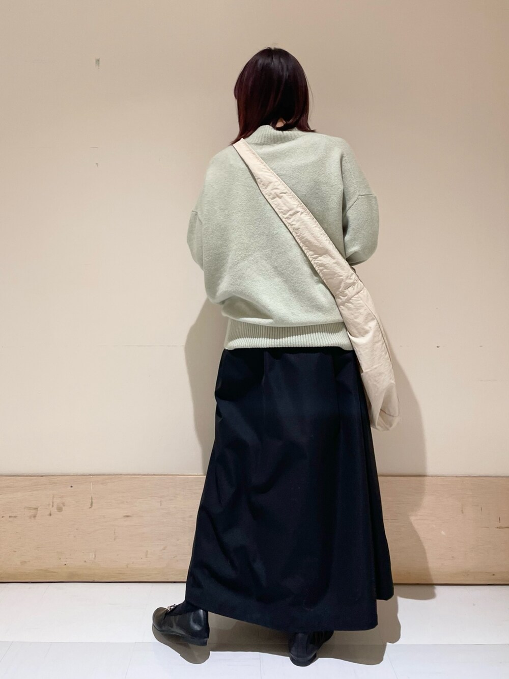 グリーン系のニット/セーター、ブラック系のスカート、グレー系のショルダーバッグを着用したレディースの冬コーディネートの6枚目の写真