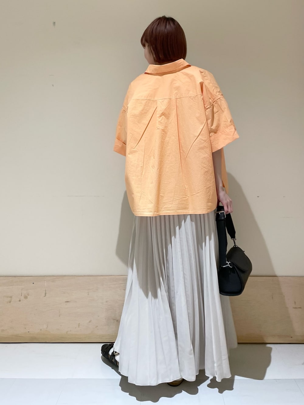 ブラック系のショルダーバッグ、ブラック系のサンダル、ホワイト系のスカートを着用したレディースの春コーディネートの6枚目の写真