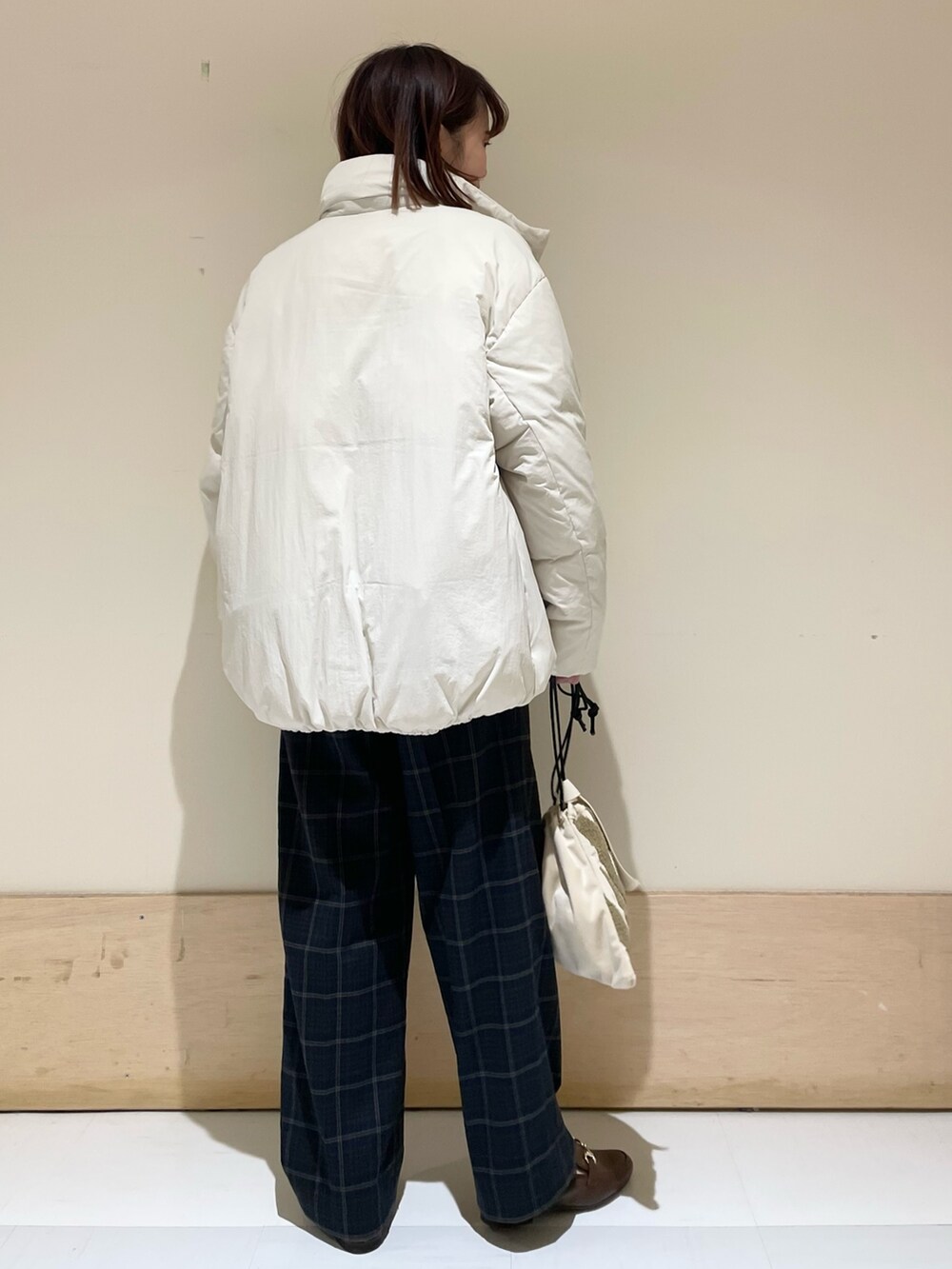 グリーン系のニット/セーター、ホワイト系のダウンジャケット/コート、ブラウン系のローファーを着用したレディースの秋コーディネートの7枚目の写真