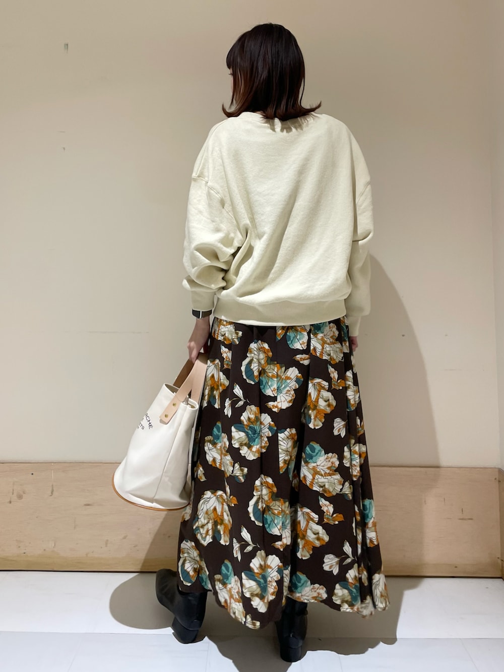 ホワイト系のスウェット、ブラウン系のスカート、ブラック系のブーツを着用したレディースの冬コーディネートの2枚目の写真