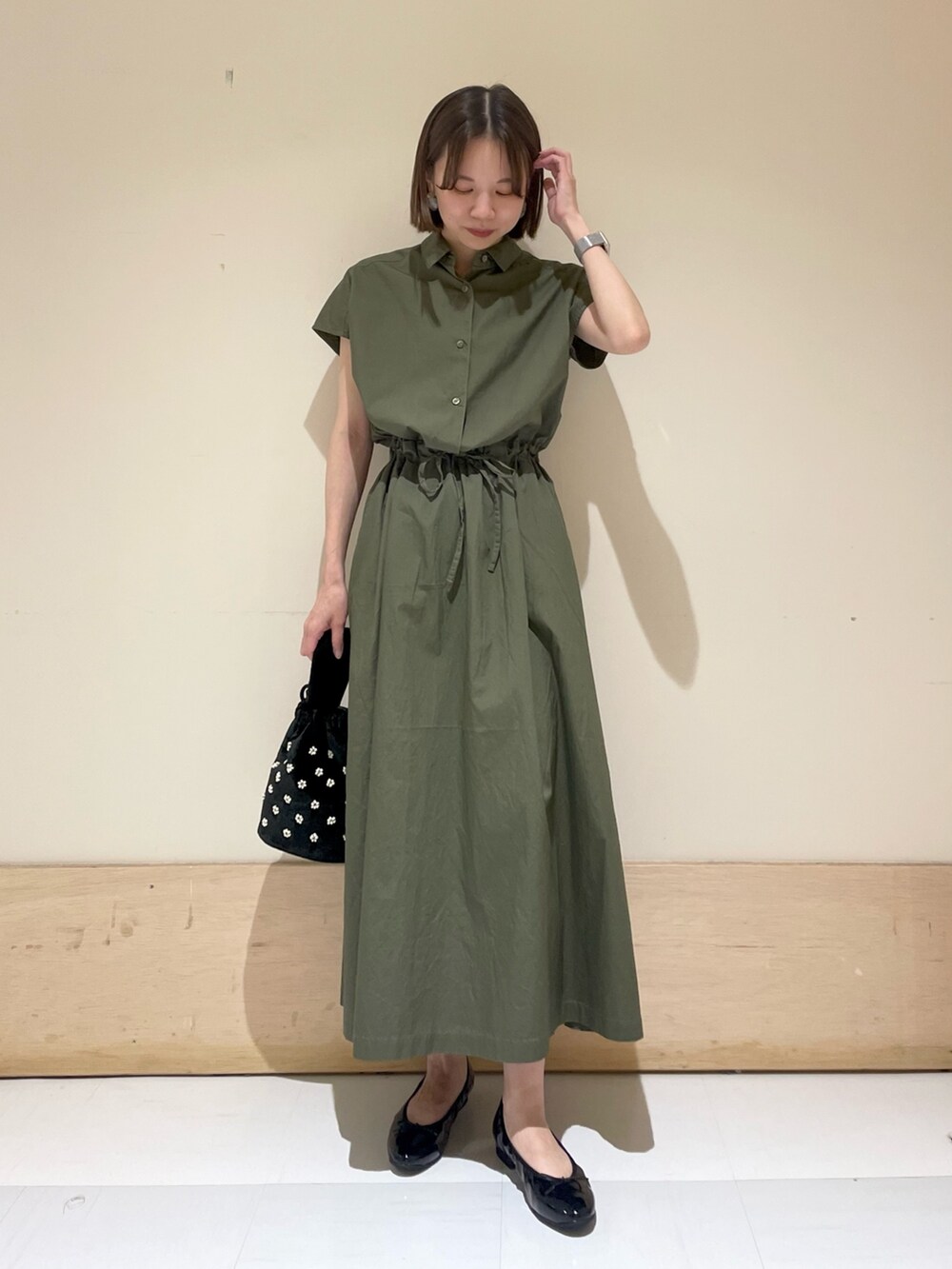 ブラック系のパンプス、ベージュ系のハンドバッグ、グリーン系のワンピースを着用したレディースの夏コーディネートの2枚目の写真