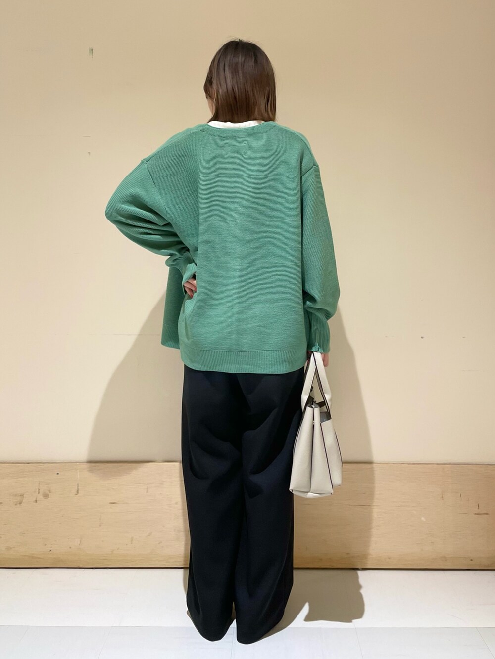 グリーン系のカーディガン/ボレロ、ホワイト系のTシャツ/カットソー、グレー系のトートバッグを着用したレディースの秋コーディネートの6枚目の写真