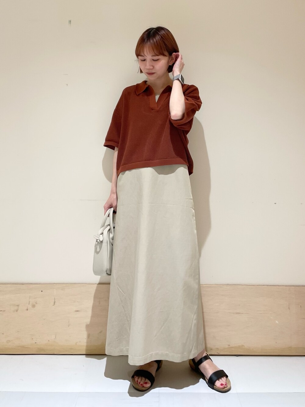 ベージュ系のワンピース、ブラック系のサンダル、ベージュ系のショルダーバッグを着用したレディースの春コーディネートの2枚目の写真