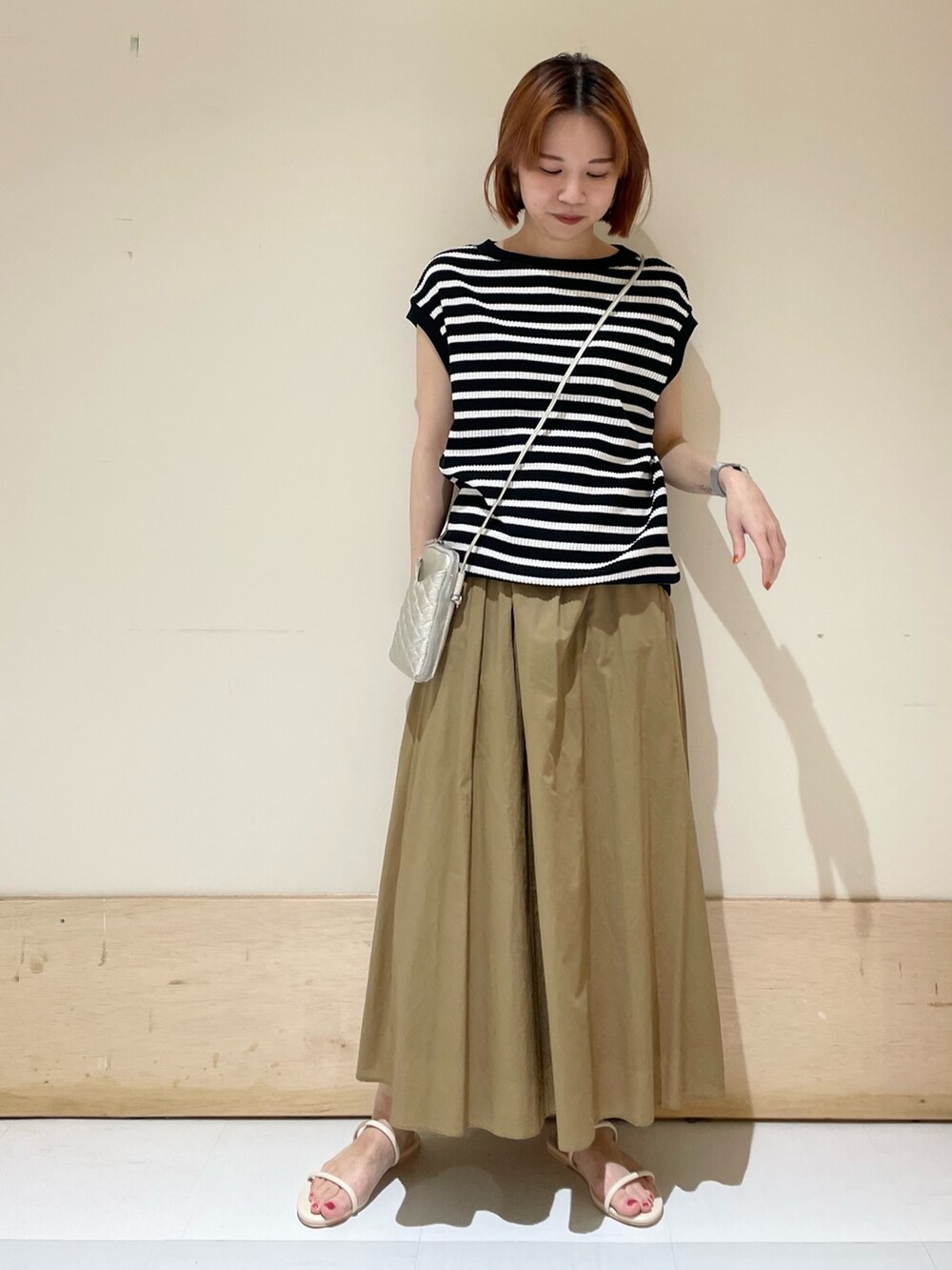 ベージュ系のスカート、ホワイト系のサンダル、ブラック系のTシャツ/カットソーを着用したレディースの夏コーディネートの3枚目の写真