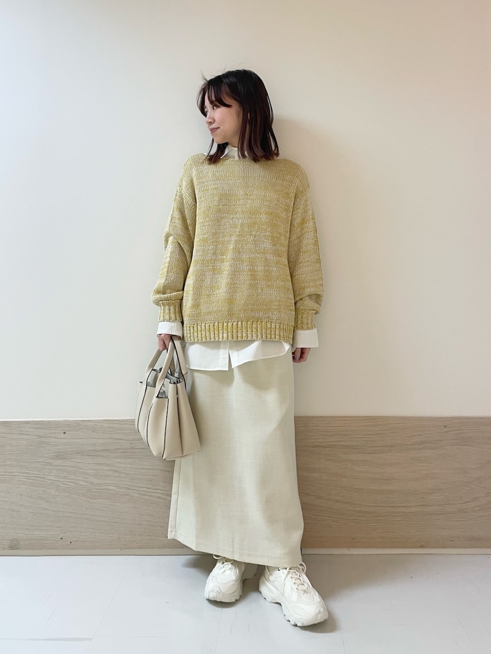 イエロー系のニット/セーター、ホワイト系のシャツ/ブラウス、ホワイト系のスカートを着用したレディースの春コーディネートの2枚目の写真