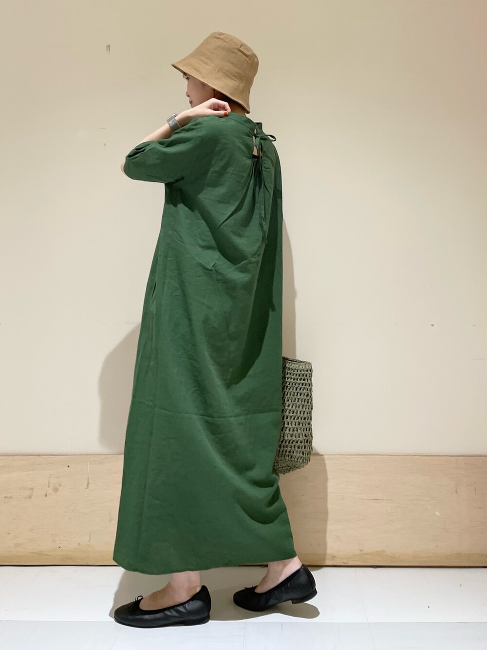 グリーン系のワンピース、ブラック系のバレエシューズ、グリーン系のかごバッグを着用したレディースの春コーディネートの6枚目の写真