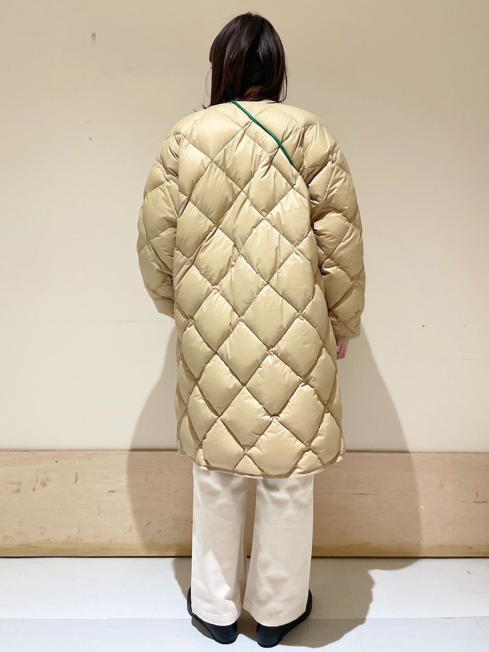 ベージュ系のデニムパンツ、ベージュ系のダウンジャケット/コート、グリーン系のニット/セーターを着用したレディースの冬コーディネートの5枚目の写真