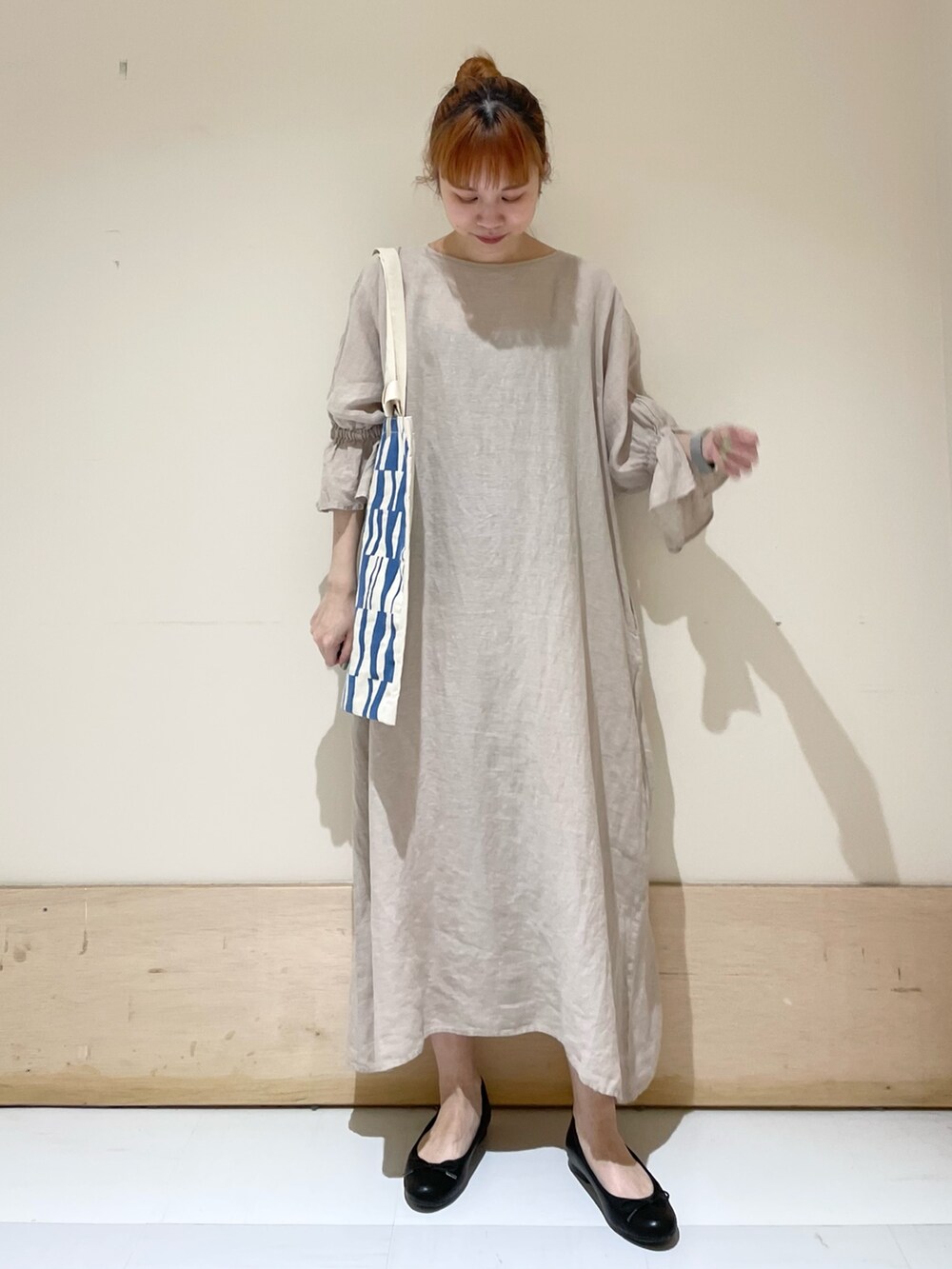 ベージュ系のワンピース、ブルー系のトートバッグ、ブラック系のバレエシューズを着用したレディースの春コーディネートの3枚目の写真